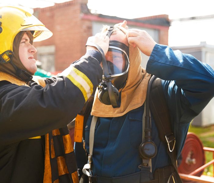 Firemen training, supervisor helping fireman with breathing apparatus at training facility
