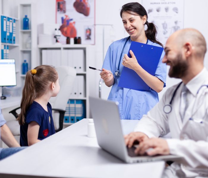 Medical staff smiling at child during consultation in home office and doctor using laptop. Healthcare physician specialist in medicine providing health care services treatment examination.